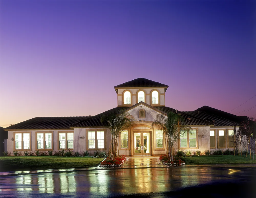 Single-story residence photographed at dusk with a central tower and illuminated windows.