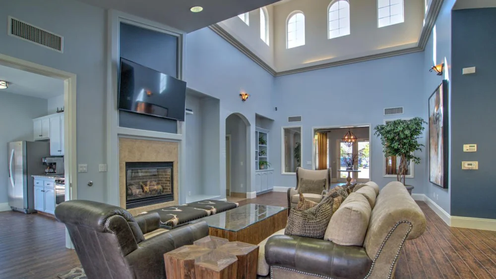 Double-height great room with arched windows, a fireplace, and an adjoining kitchen.
