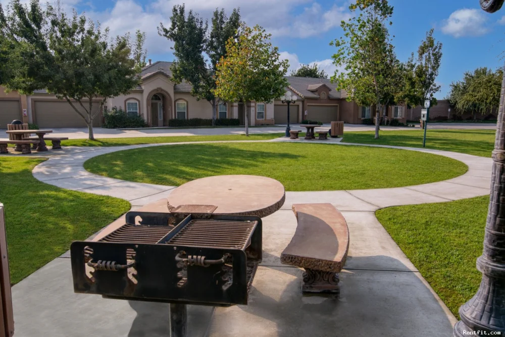 Landscaped apartment-community grounds with curved paths and shared seating.